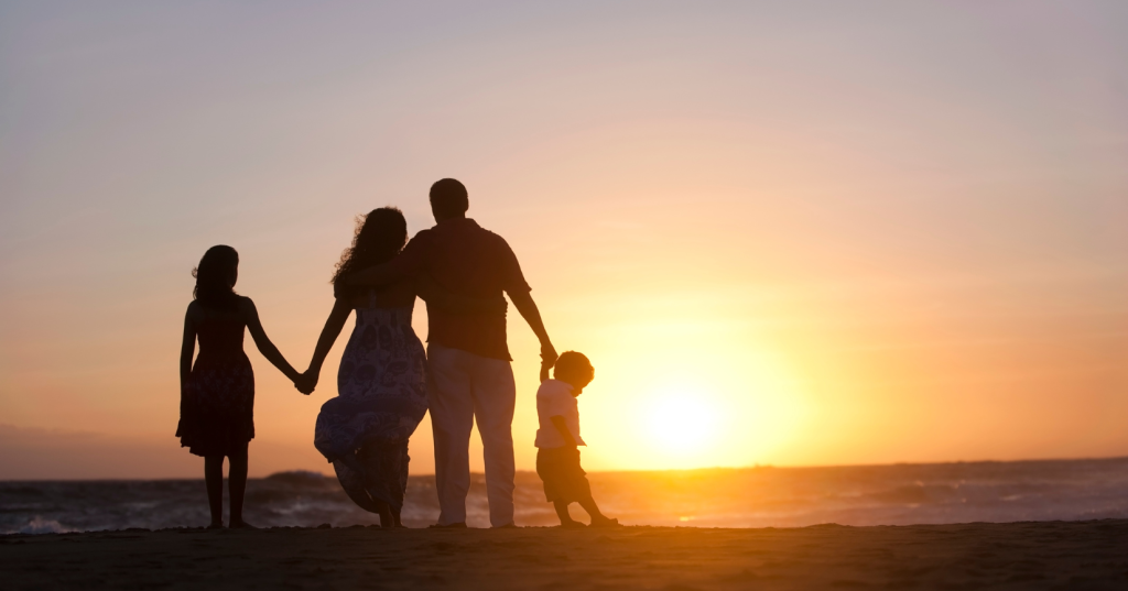 a family on the beach holding hands and looking at the sunset
