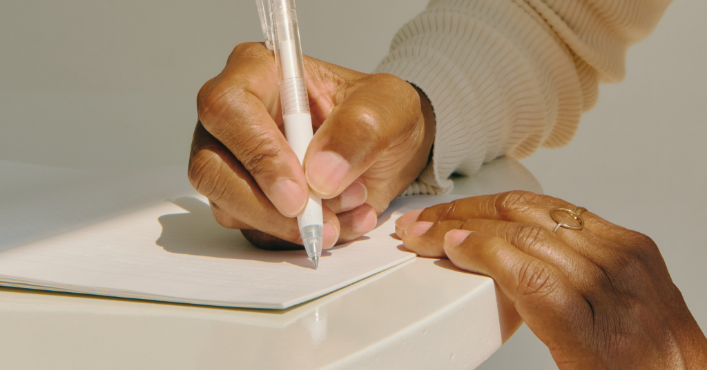 someone holding a pen writing in a journal to record wishes