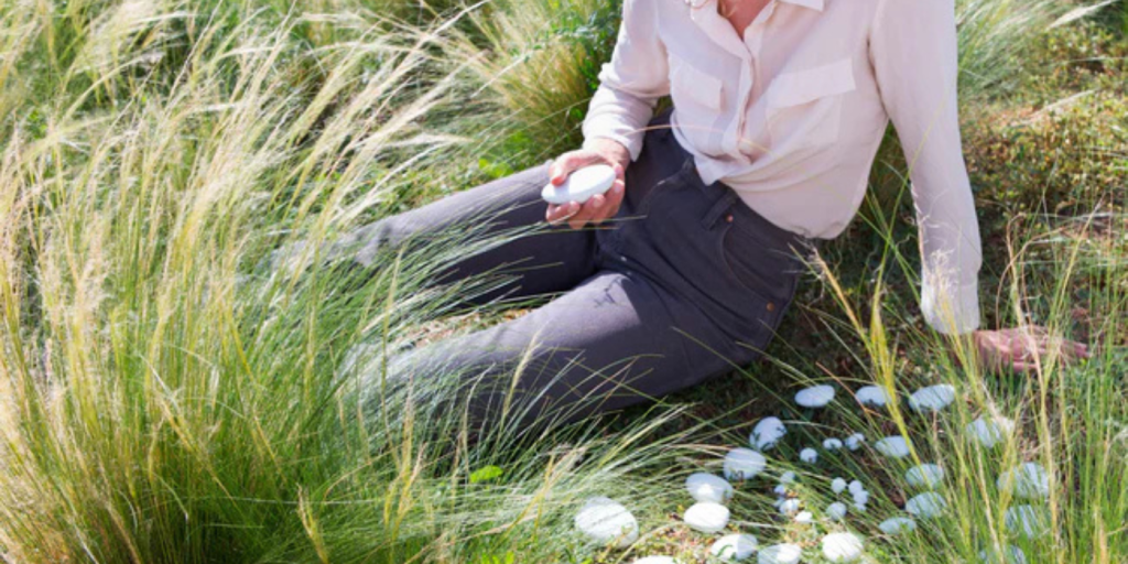 a woman in the grass holding some cremation stones. 