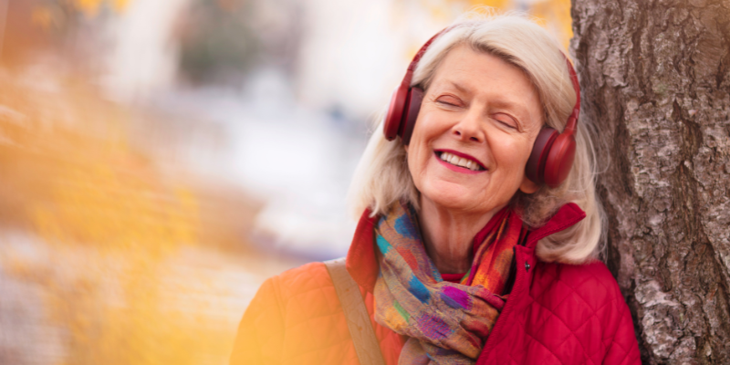 an older lady wearing headphones enjoying listening to music